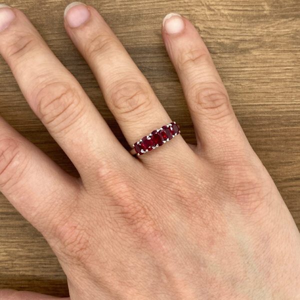 Five-ruby ring on a hand.
