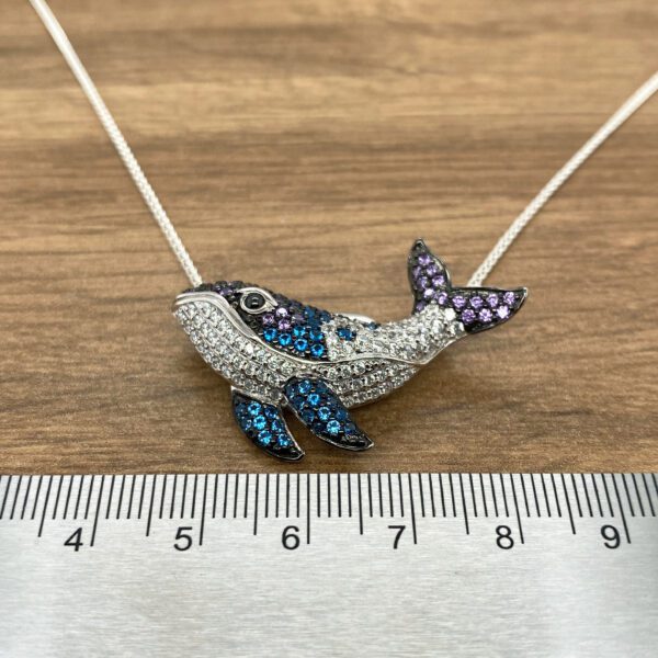 Silver whale necklace with blue gems.