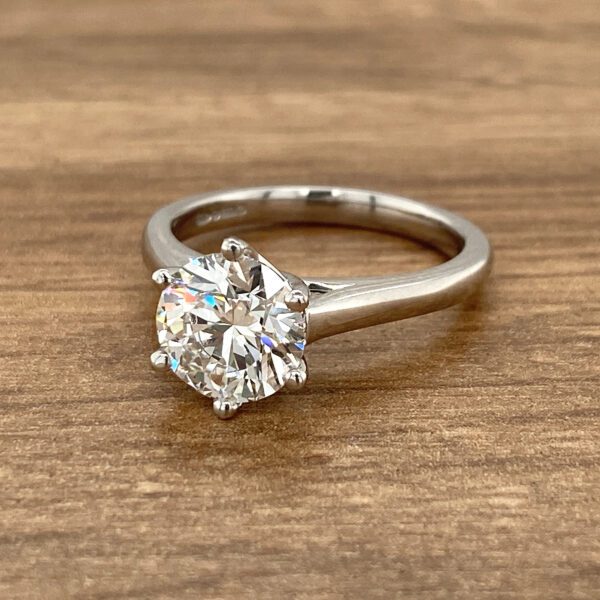 Solitaire diamond ring on wood.