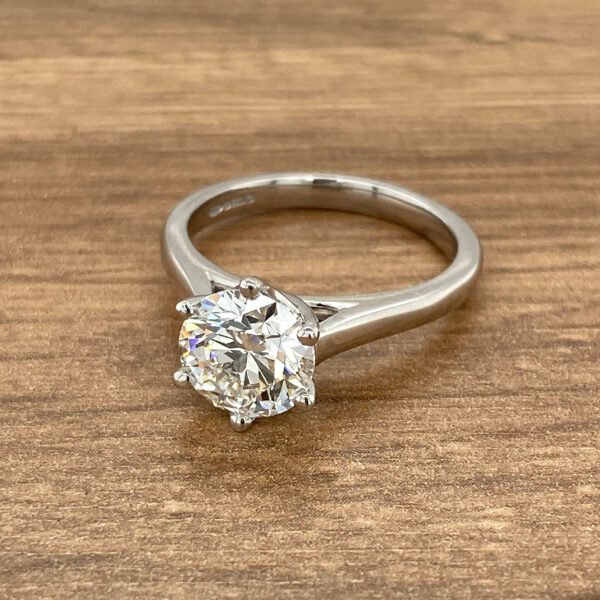 Diamond solitaire engagement ring on wood.