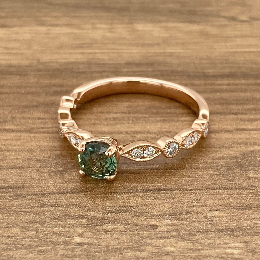 Rose gold ring with green gemstone and diamonds.