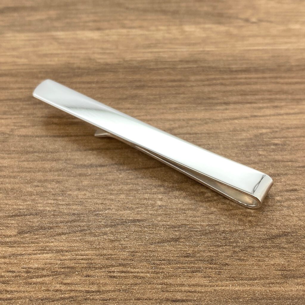 Silver tie bar on wood background.