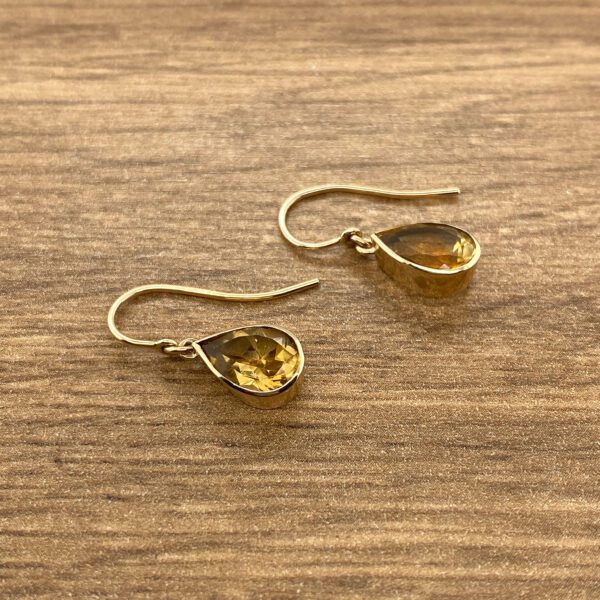 Gold teardrop earrings with amber stones.
