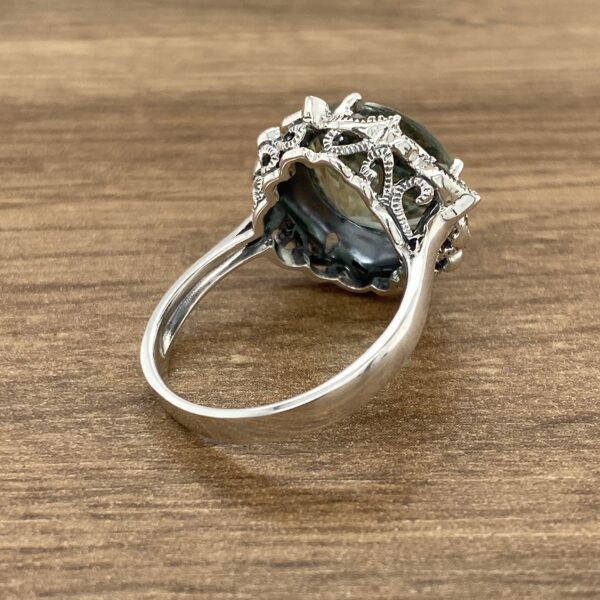 Silver ring with green gemstone setting.