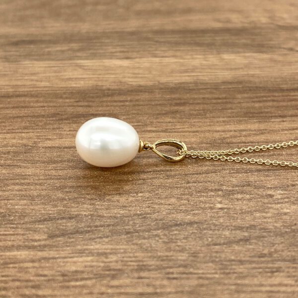 Gold necklace with single pearl pendant.