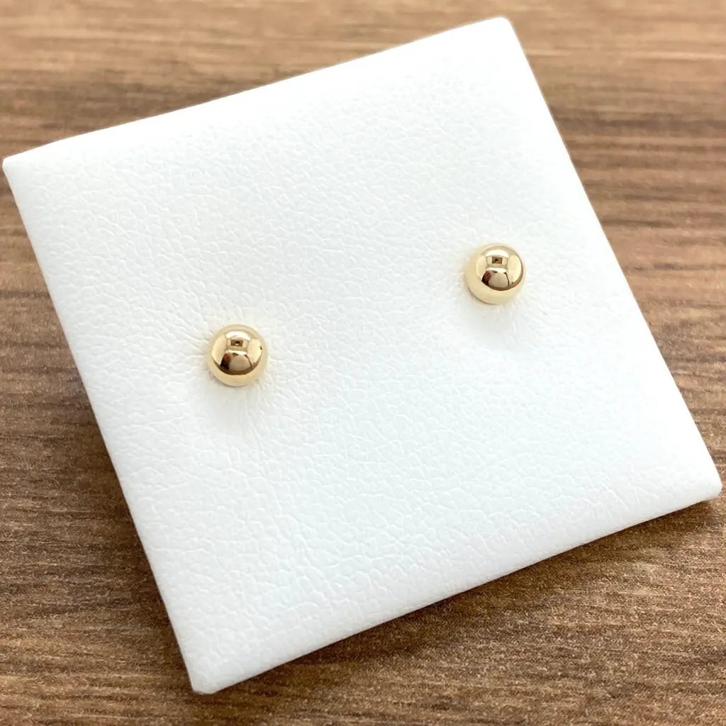 Gold ball stud earrings on display.