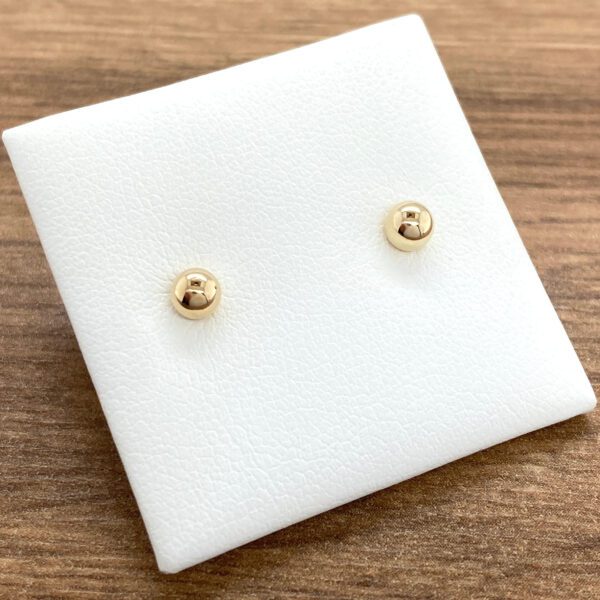 Gold ball stud earrings on display.
