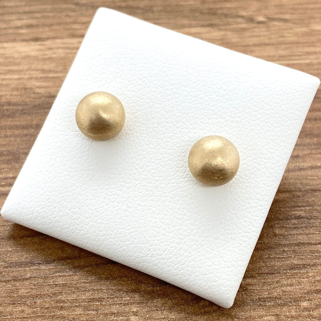 Gold ball stud earrings on display.