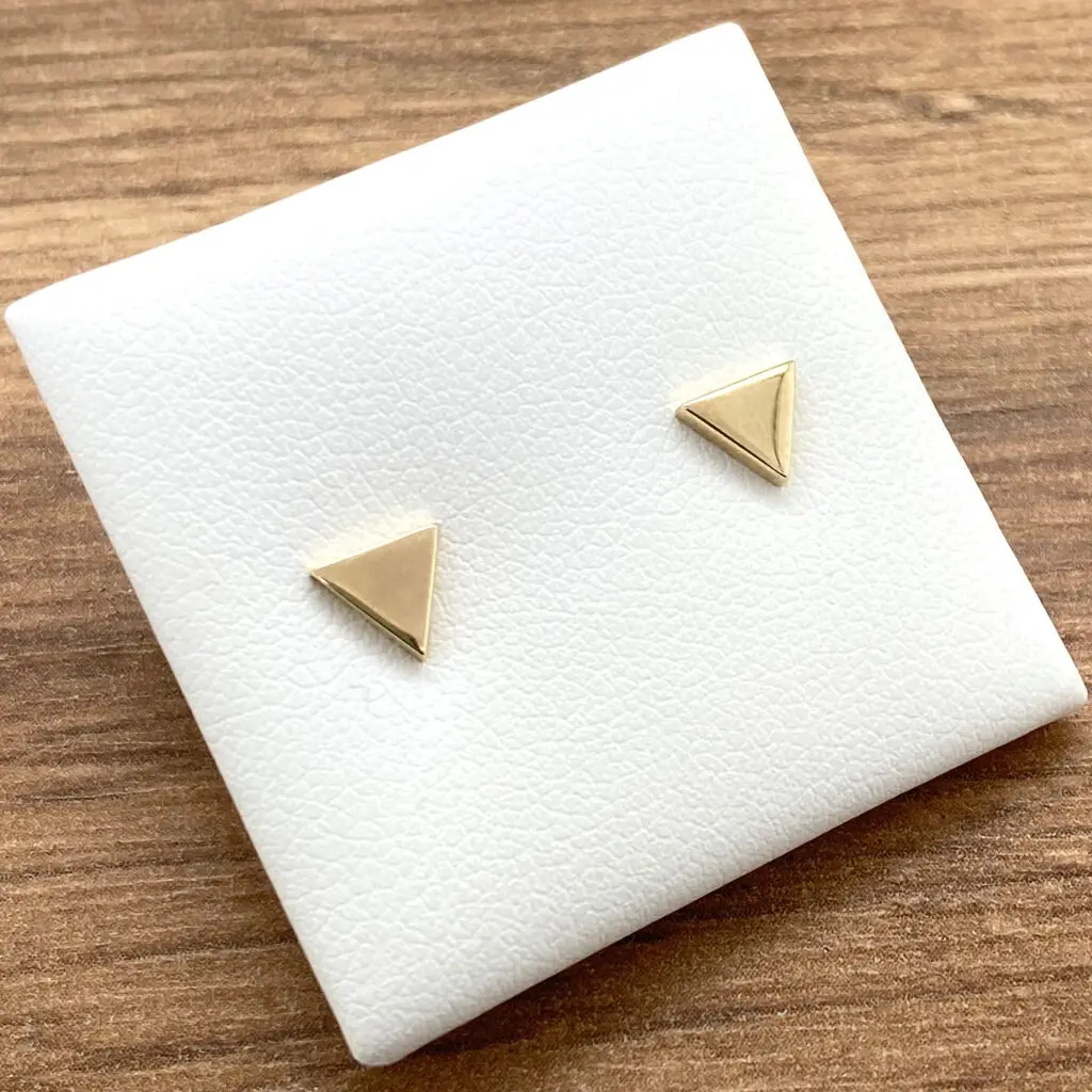 Gold triangle stud earrings on display.