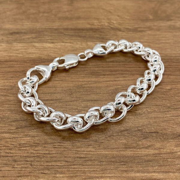 Silver chain bracelet on wood background.