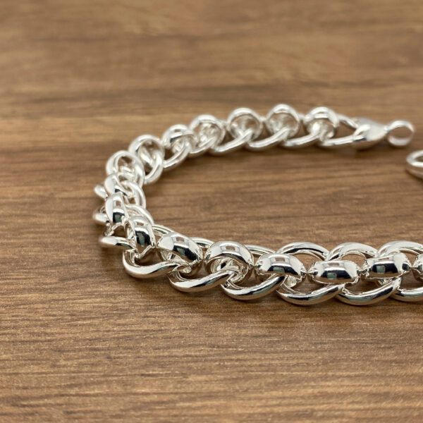 Silver chain bracelet on wood background.