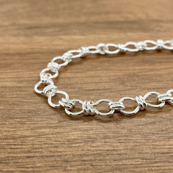 Silver linked bracelet on wood.