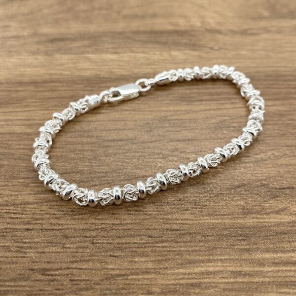 Silver Byzantine bracelet on wood.