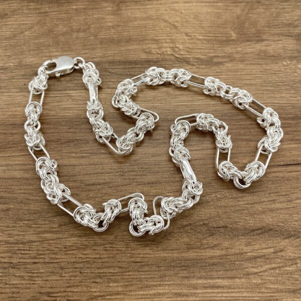 Silver chain necklace, intricate design.