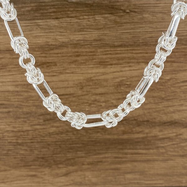 Silver chain necklace, intricate knots.