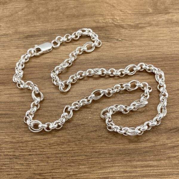 Silver chain necklace on wood background.
