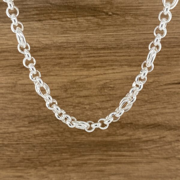 Silver chain necklace on wood background.