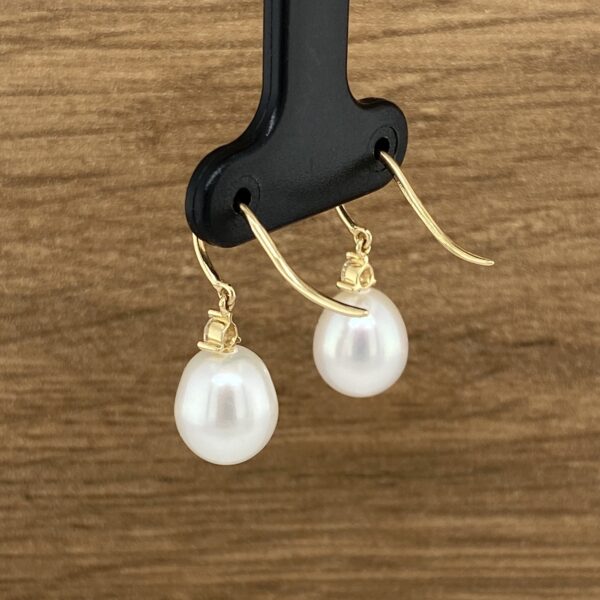 Gold pearl drop earrings on display.