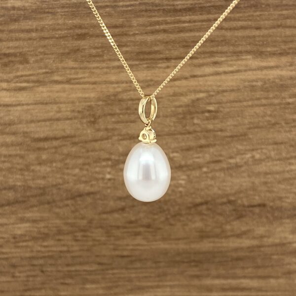Gold chain with teardrop pearl pendant.