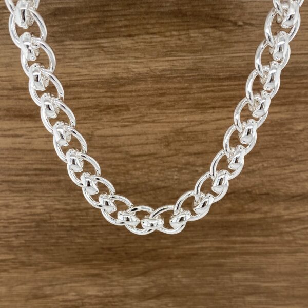 Silver chain necklace on wood background.