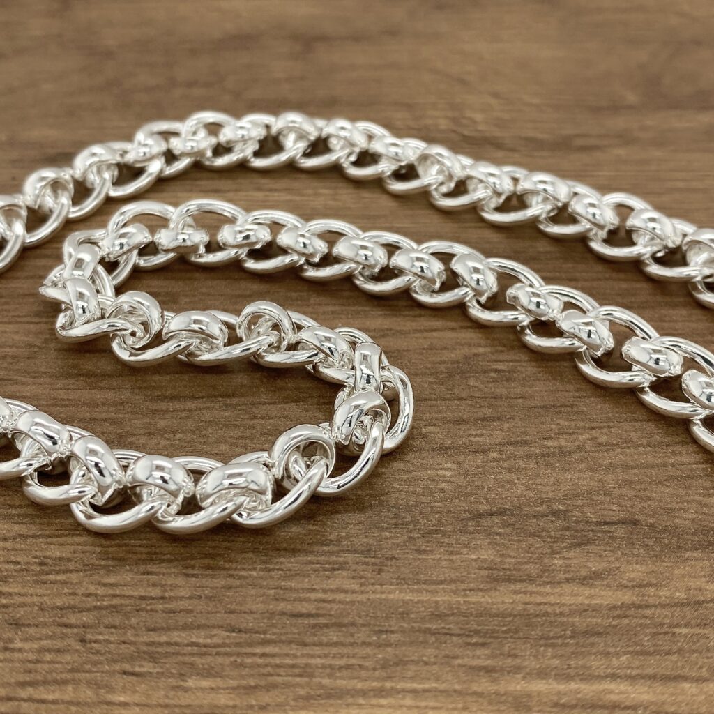 Silver curb chain necklace on wood.