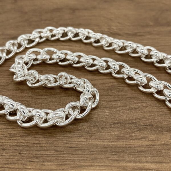 Silver curb chain necklace on wood.