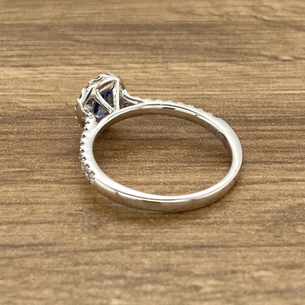 Blue sapphire halo ring on wood.