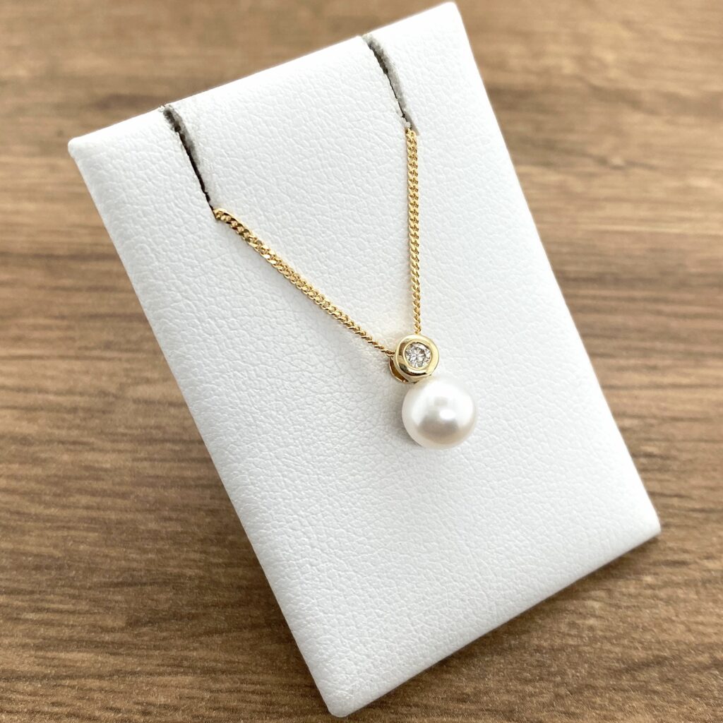 Gold pearl necklace with diamond accent.