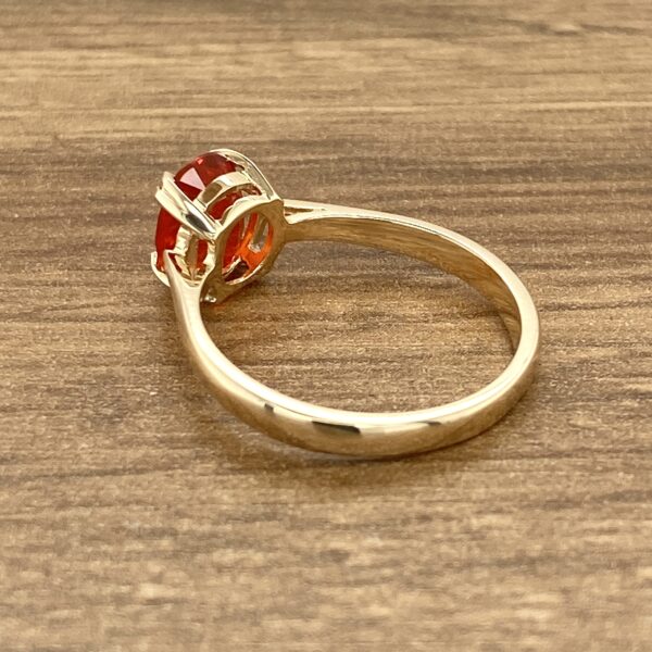 Gold ring with red oval gemstone.