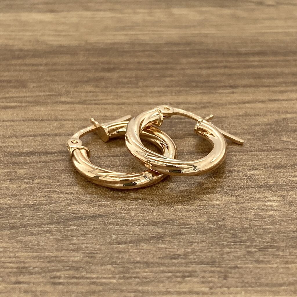 Gold hoop earrings on wood.